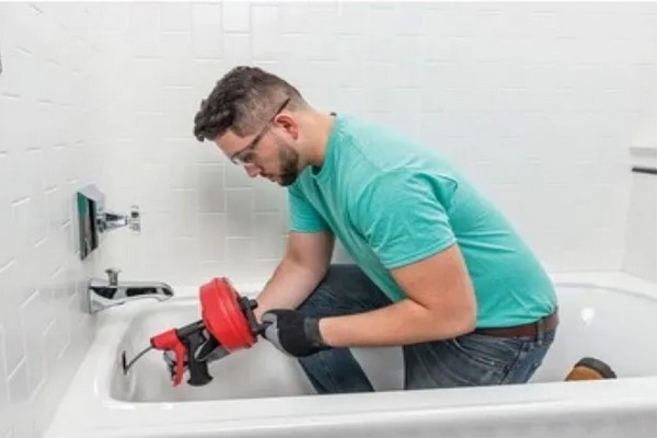 professionele loodgieter die een badkuip ontstopt