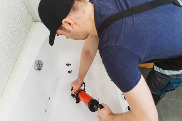 professionele loodgieter die een badkuip ontstopt