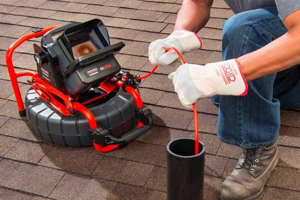 ontstopper die met een camera een verstopte leiding inspecteert