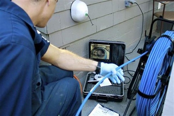 ontstopper die met een camera een verstopte leiding inspecteert